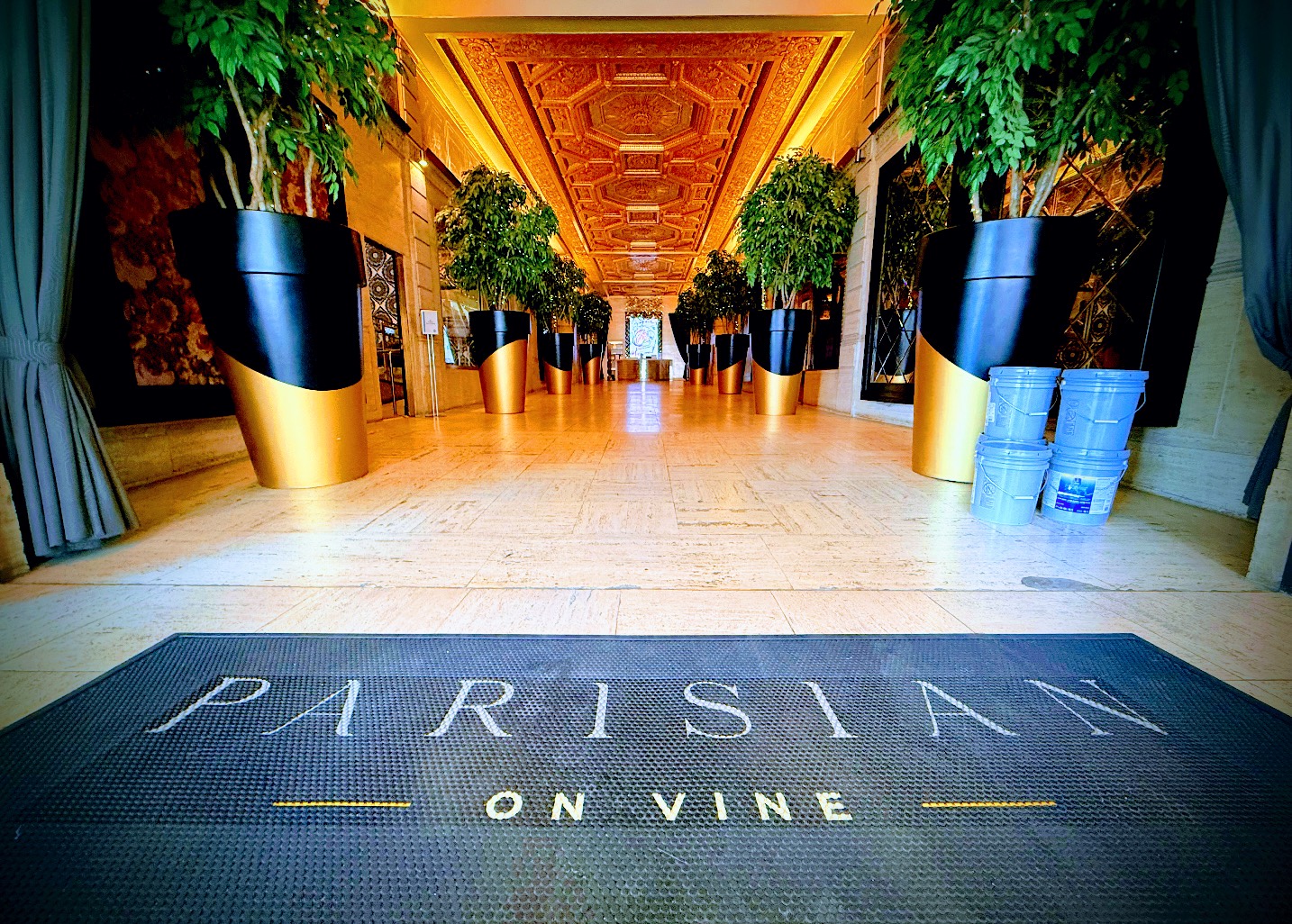 Gold-coffered corridor of the Parisian on Vine with a black and gold entrance mat