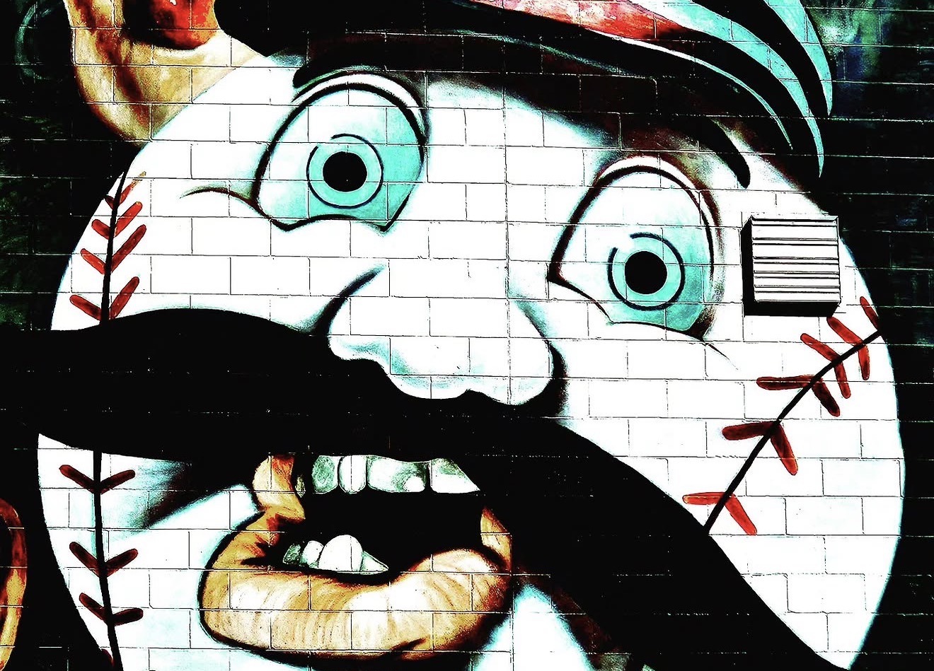 Mural of a cartoon baseball face on a brick wall