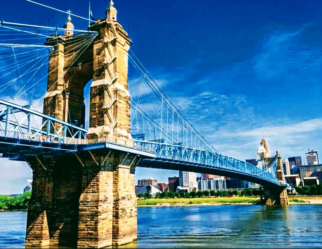 Roebling suspension bridge with stone towers and blue cables over the river