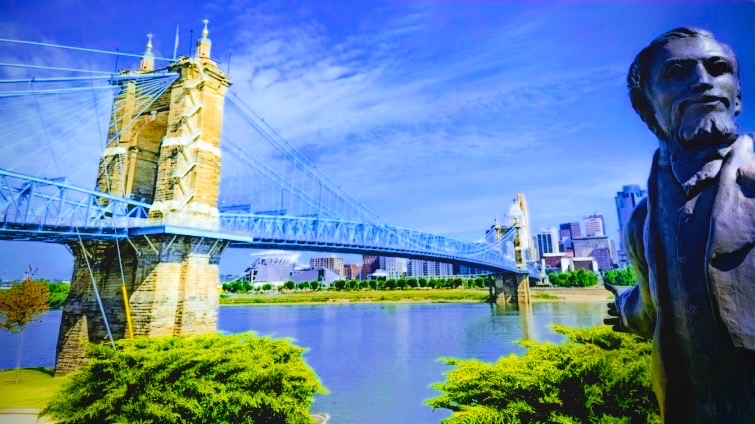 Roebling statue and the suspension bridge under a blue summer sky
