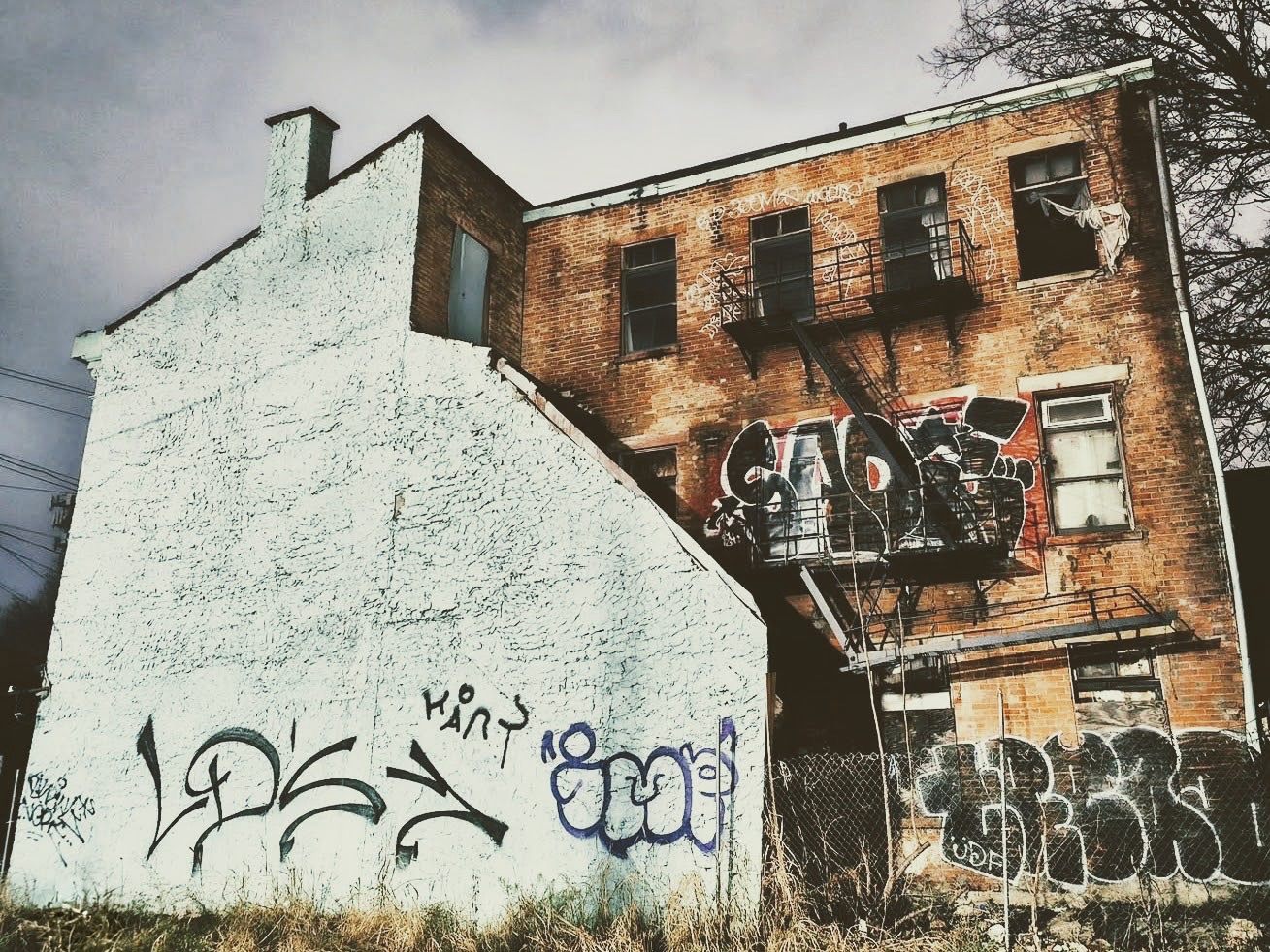 Derelict brick building covered in graffiti under a grey sky