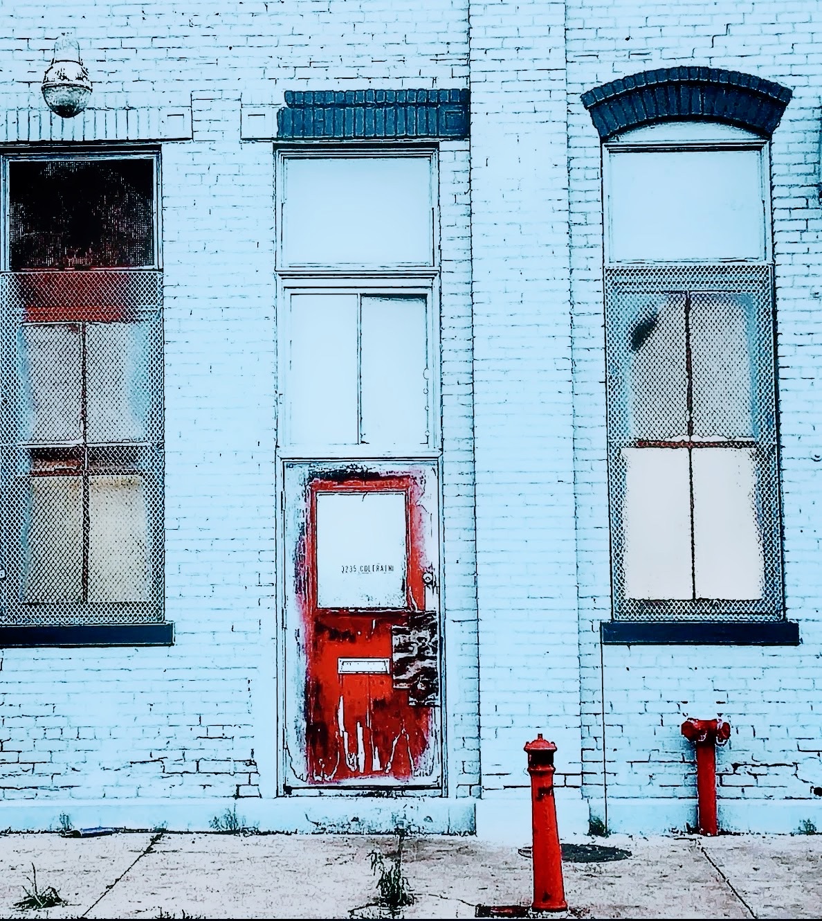 Pale blue brick facade with a red door and two red hydrants
