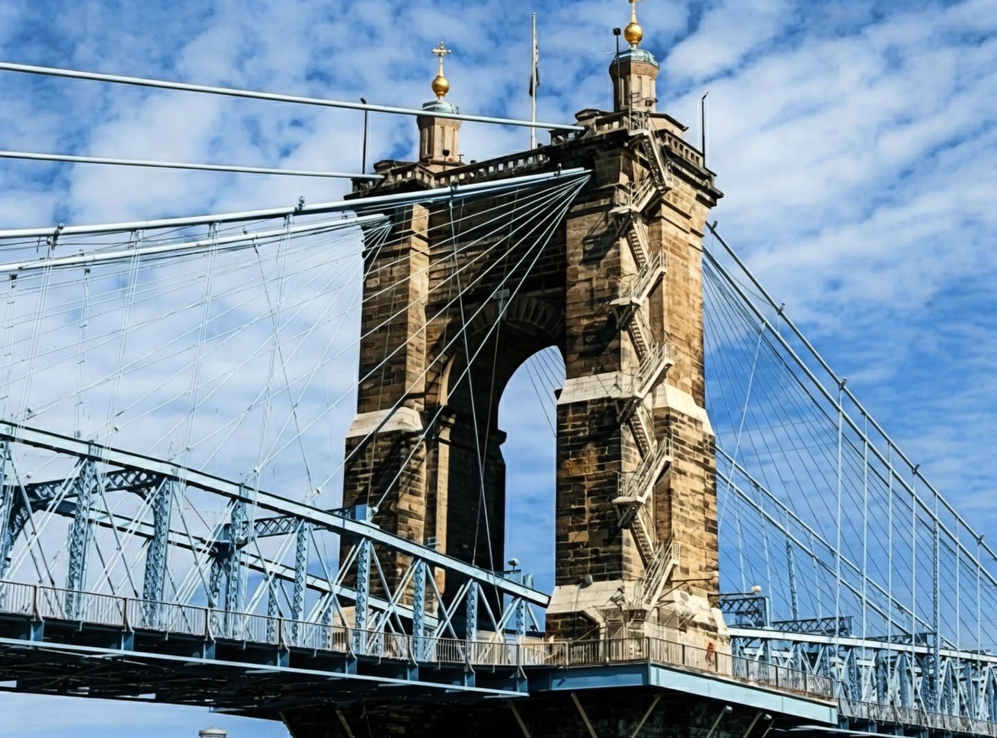 Stone tower and cables of the suspension bridge against blue sky
