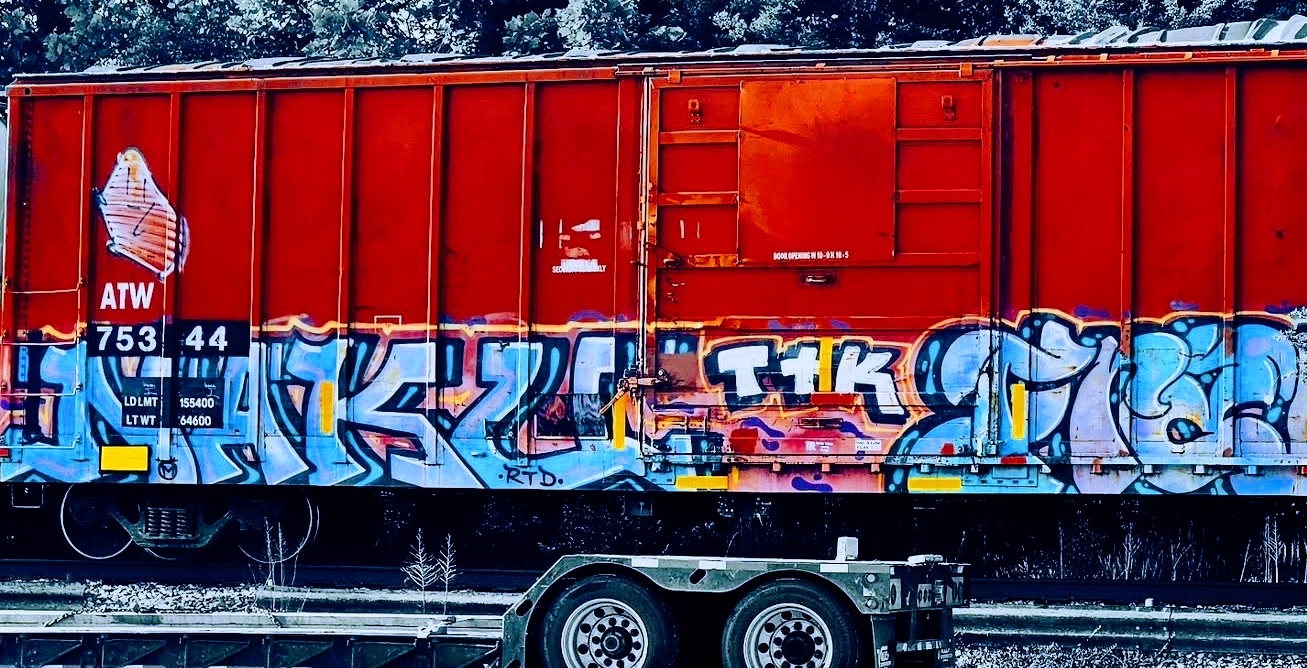 Red freight boxcar covered in blue and white graffiti