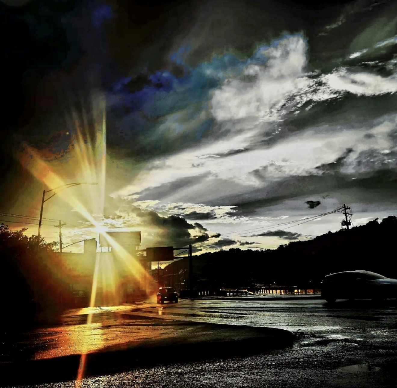 Sunburst over a wet street under a dramatic sky
