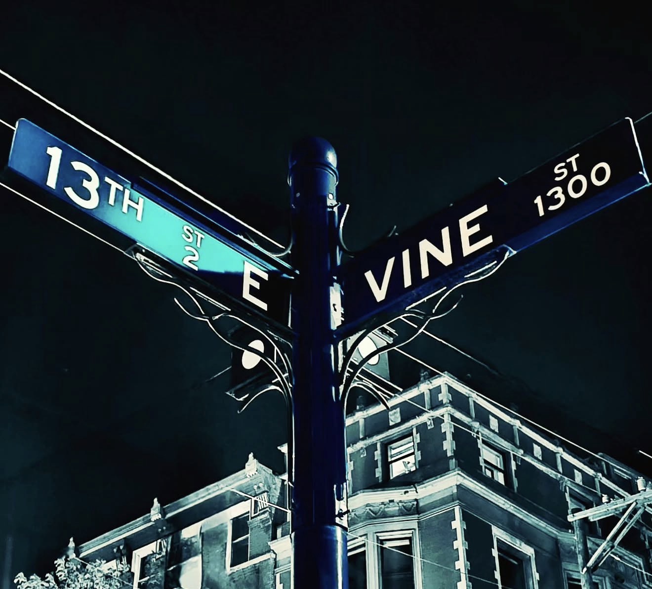 Blue street signs for 13th Street and Vine Street at night