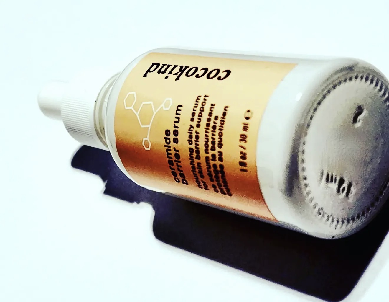 cocokind ceramide barrier serum lying on its side on white with a hard shadow