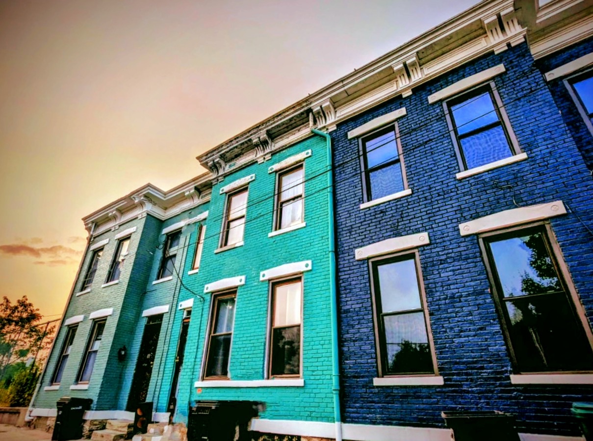 Teal and blue painted brick row houses at sunset