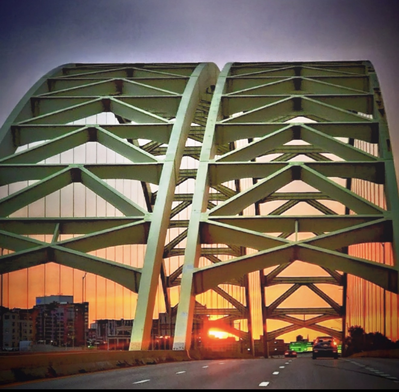 Yellow bridge trusses against an orange sunset