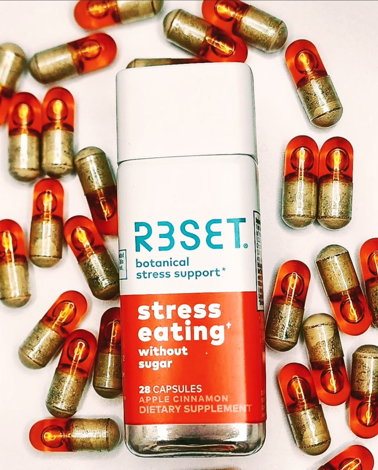 RESET botanical stress support bottle surrounded by scattered amber capsules