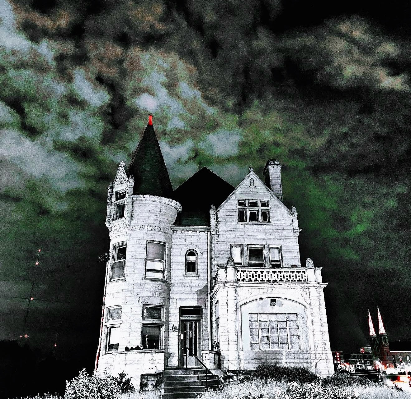 Turreted stone mansion glowing white against a dark stormy sky
