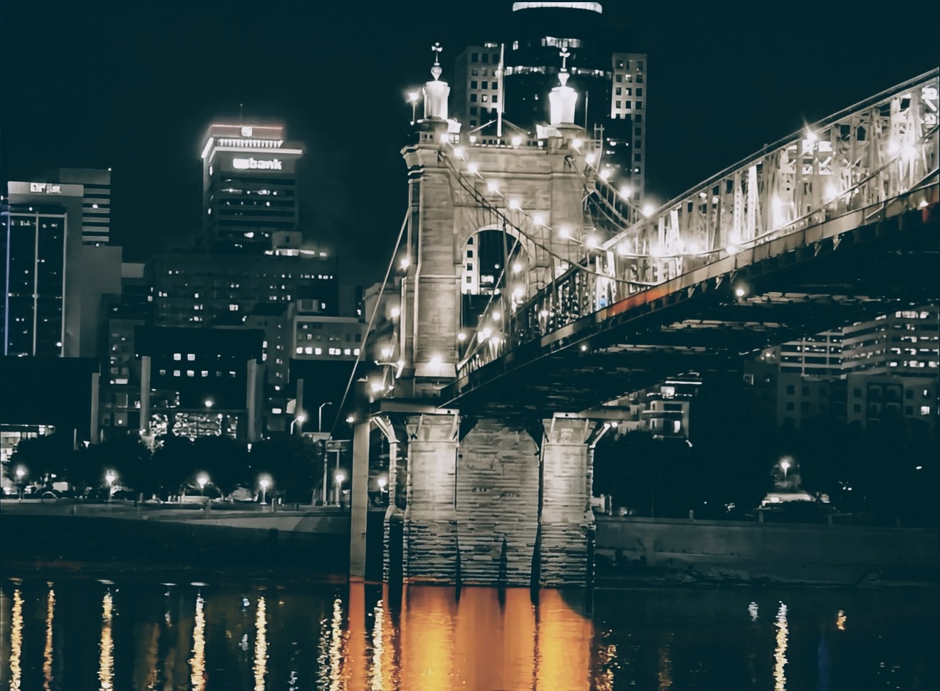 Roebling Bridge at night with city lights reflected in the water