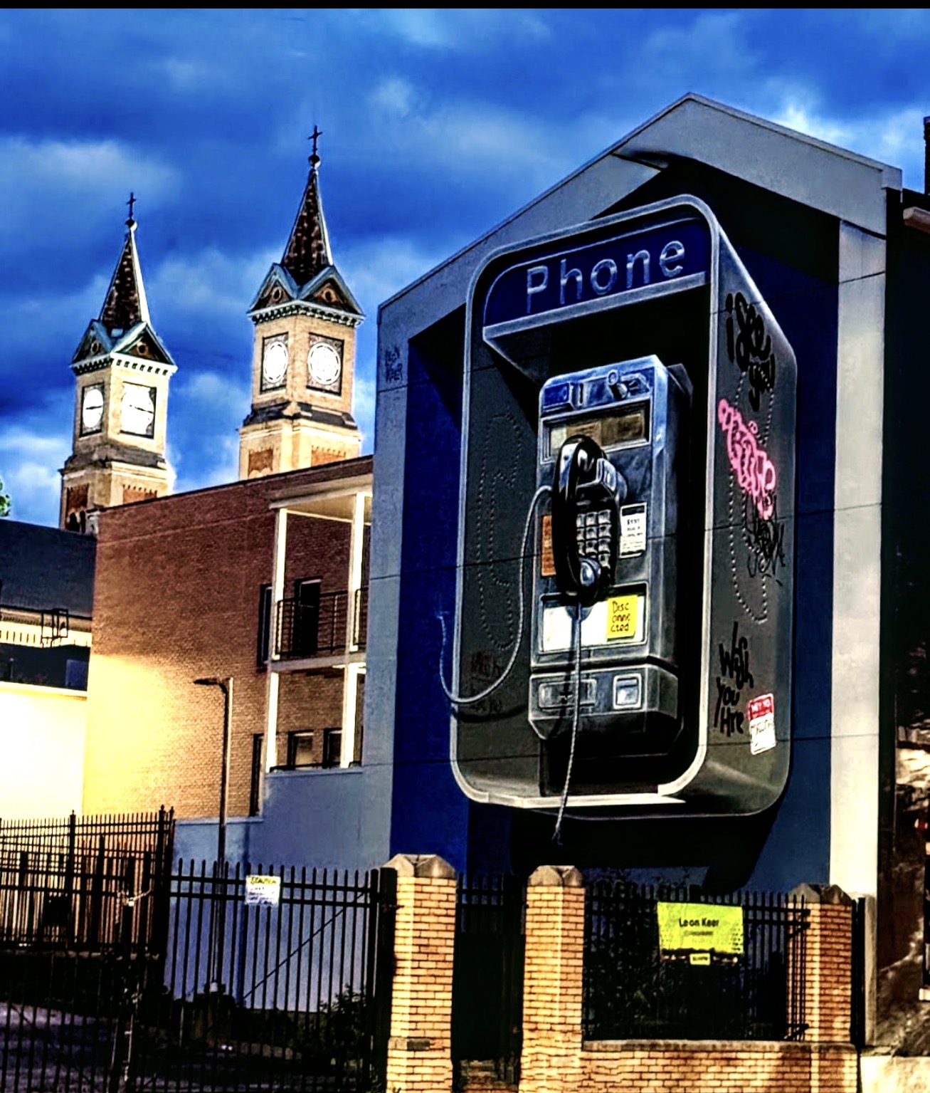 Mural of a vintage payphone on a blue building at dusk